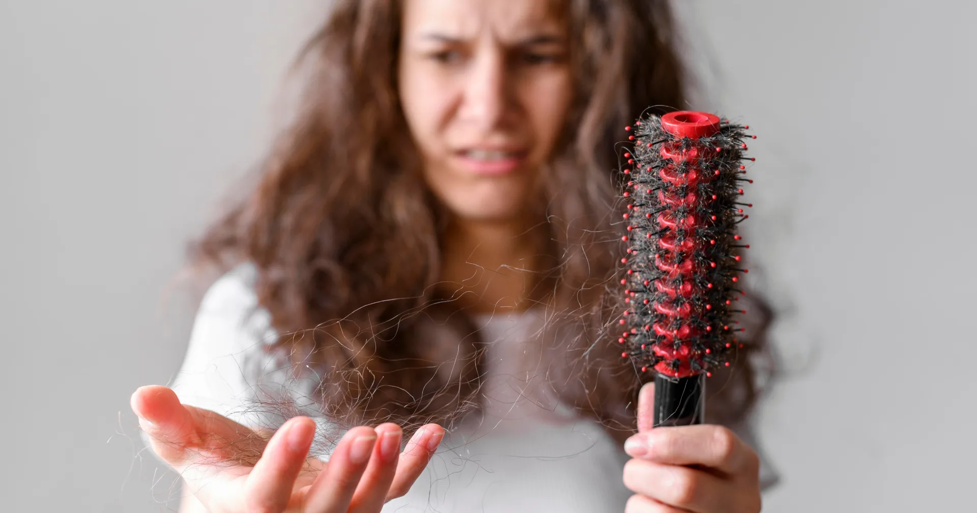 Woman concerned by hair loss while holding a hairbrush
